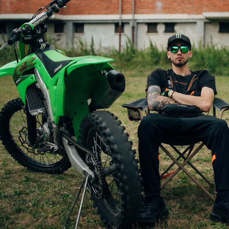 The KX450 parked on the grass, Azza sitting next to it