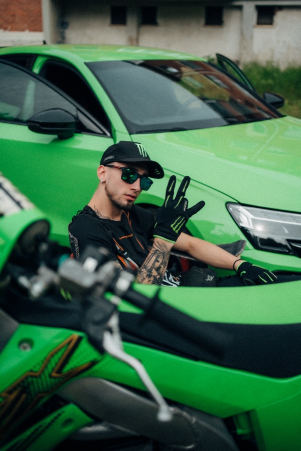 Azza throwing a hand sign between the bike and the car